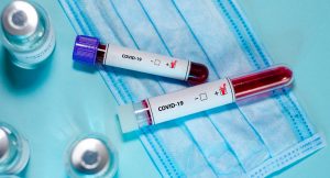Test tube with positive Coronavirus test blood sample and vaccin